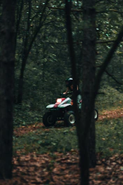 An ATV speeding through a dusty trail surrounded by lush forest.