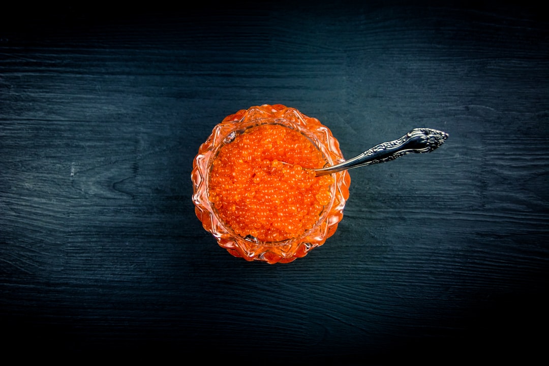 Red caviar in glassware on a black wooden background. Top view