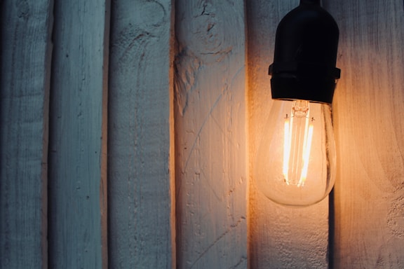 black sconce lamp turned on on white wall