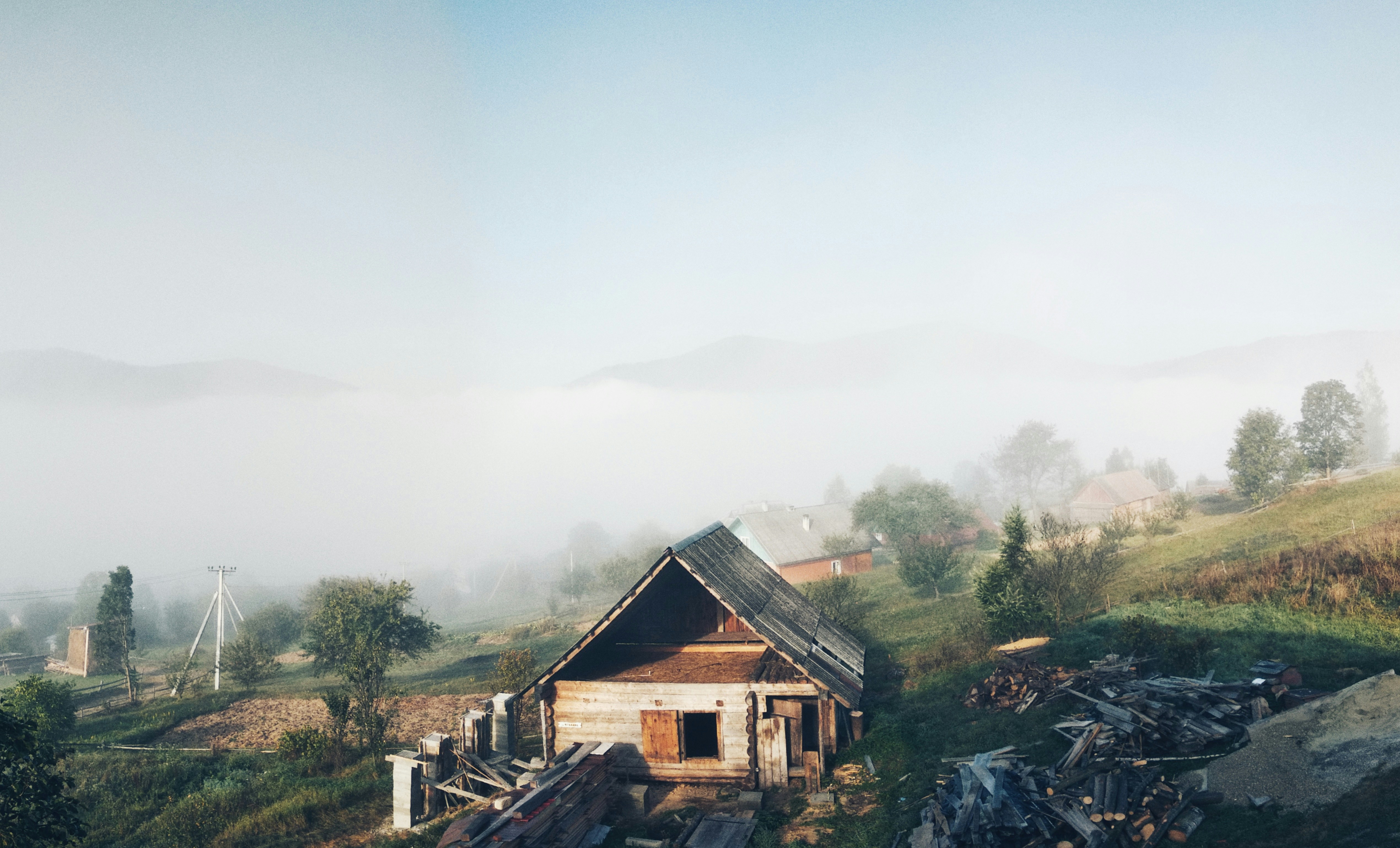 brown wooden house near green trees under white sky during daytime