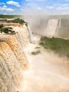 waterfalls on green grass field during daytime