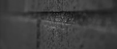 Close-up of cracked concrete casting sharp, abstract shadows in monochrome tones.