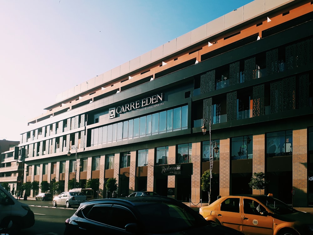 Coches aparcados frente a un edificio de hormigón marrón y blanco durante el día