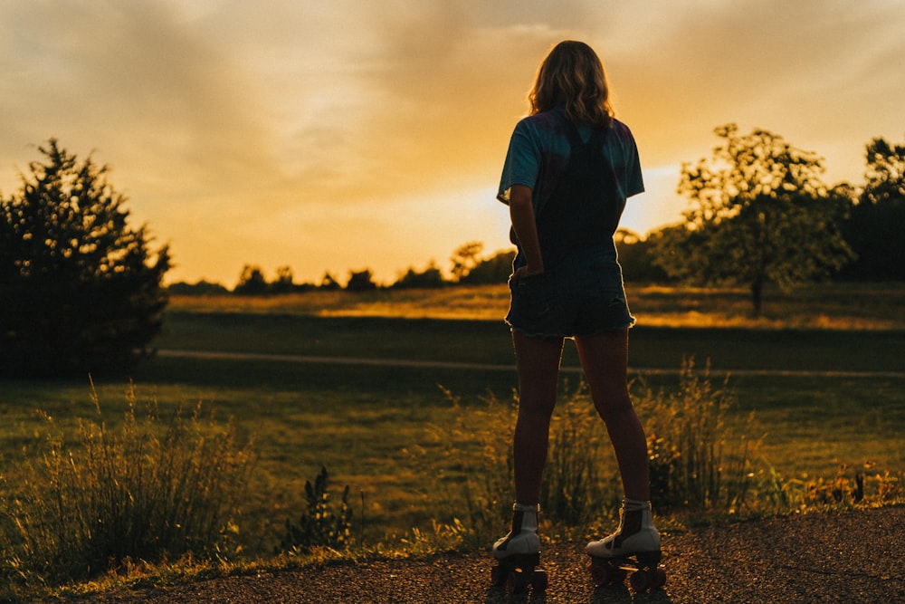 woman in blue t-shirt and black skirt standing on green grass field during daytime