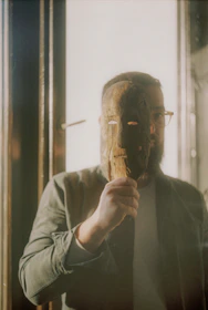 man in gray long sleeve shirt holding brown wooden stick