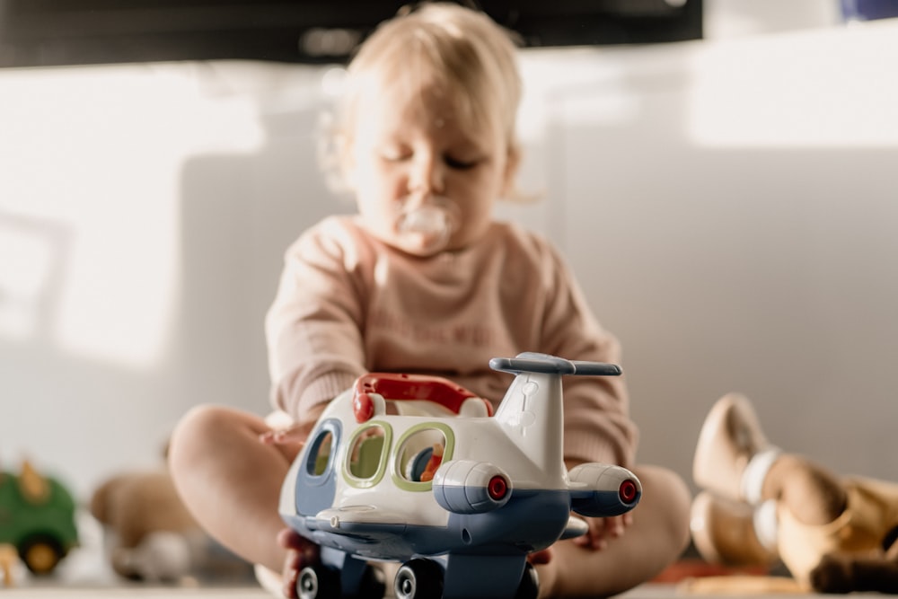 baby in white shirt riding blue and white ride on toy car