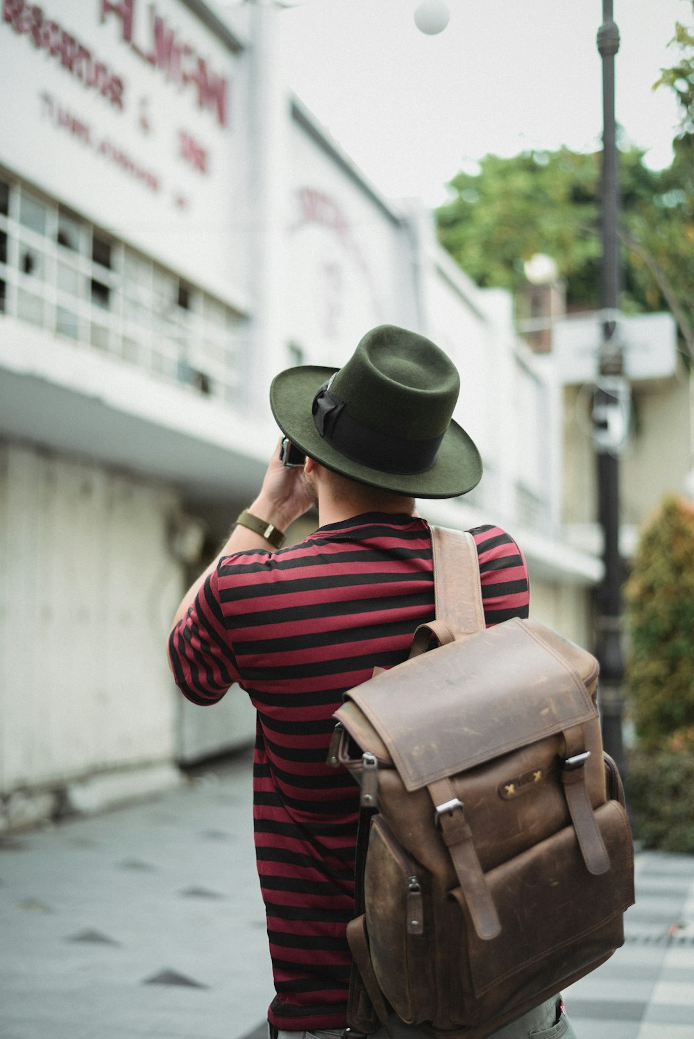 man in red and white striped long sleeve shirt wearing brown leather backpack