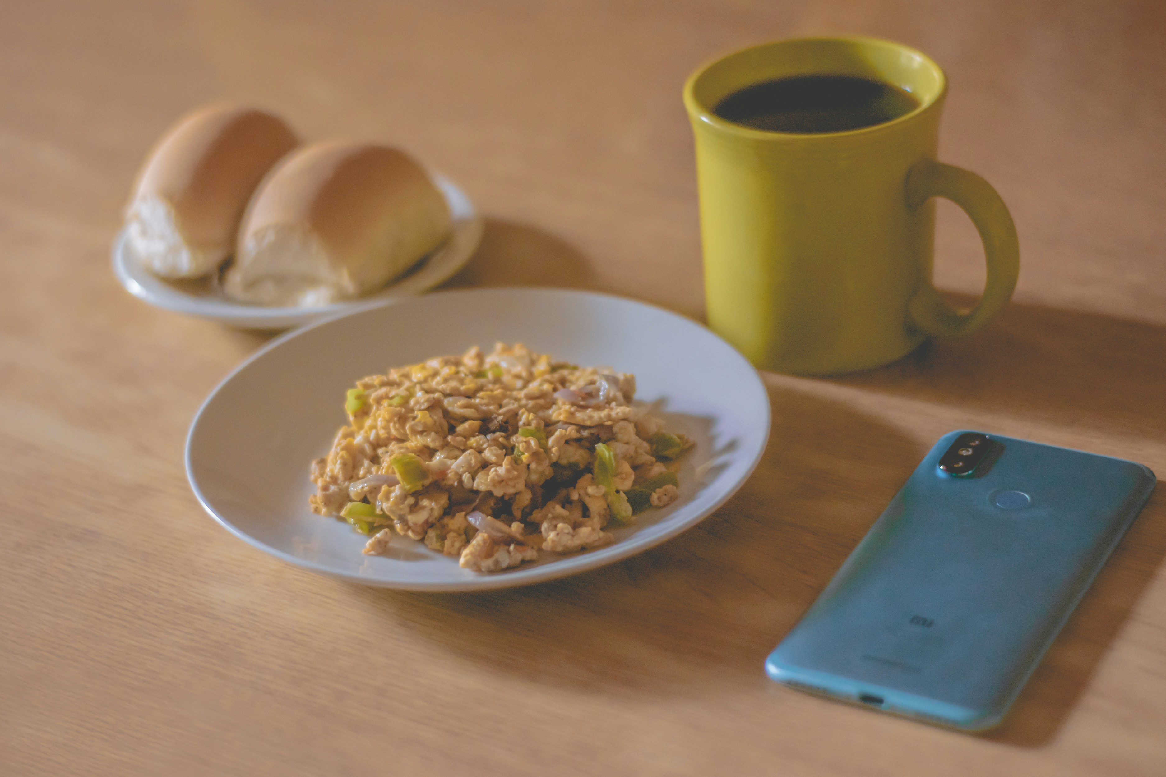 grüner Keramikbecher neben weißem Keramikteller mit Essen