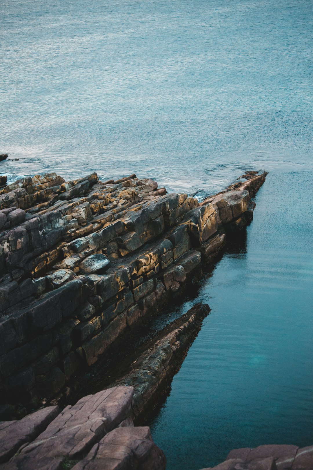 brown and gray rock formation beside body of water during daytime