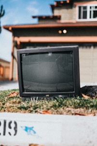 A friendly technician collecting old electronics from a smiling family at their doorstep in a sunny neighborhood.