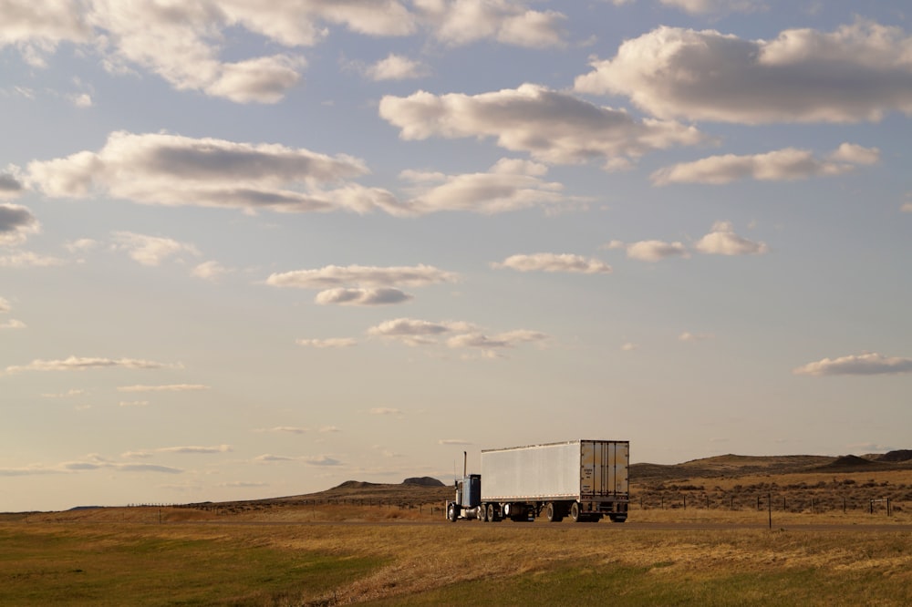 white and blue truck on green grass field under white clouds during daytime