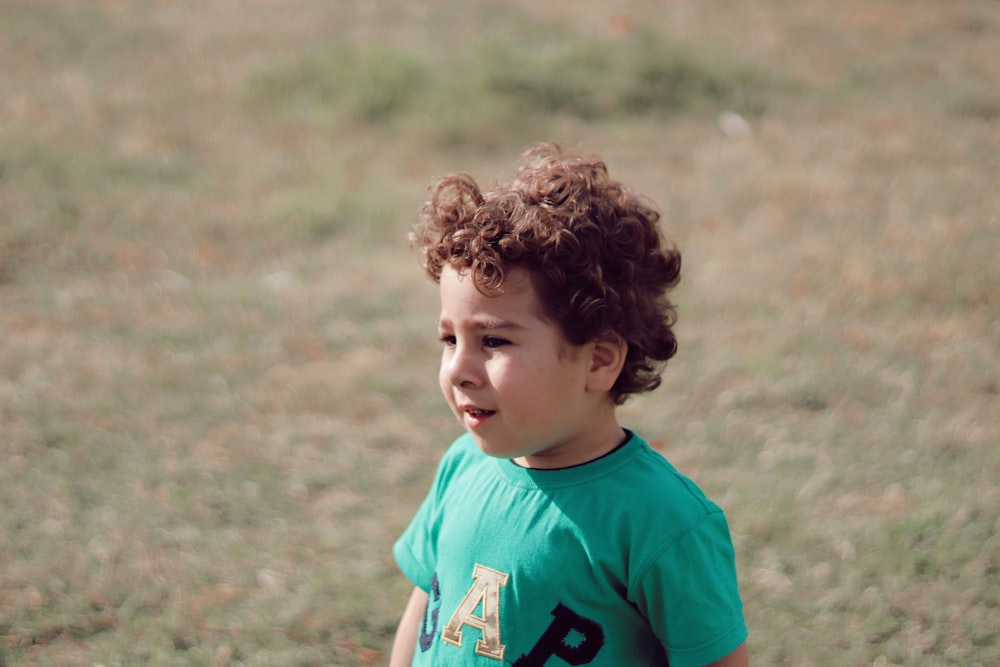 boy in blue crew neck t-shirt standing on brown grass field during daytime