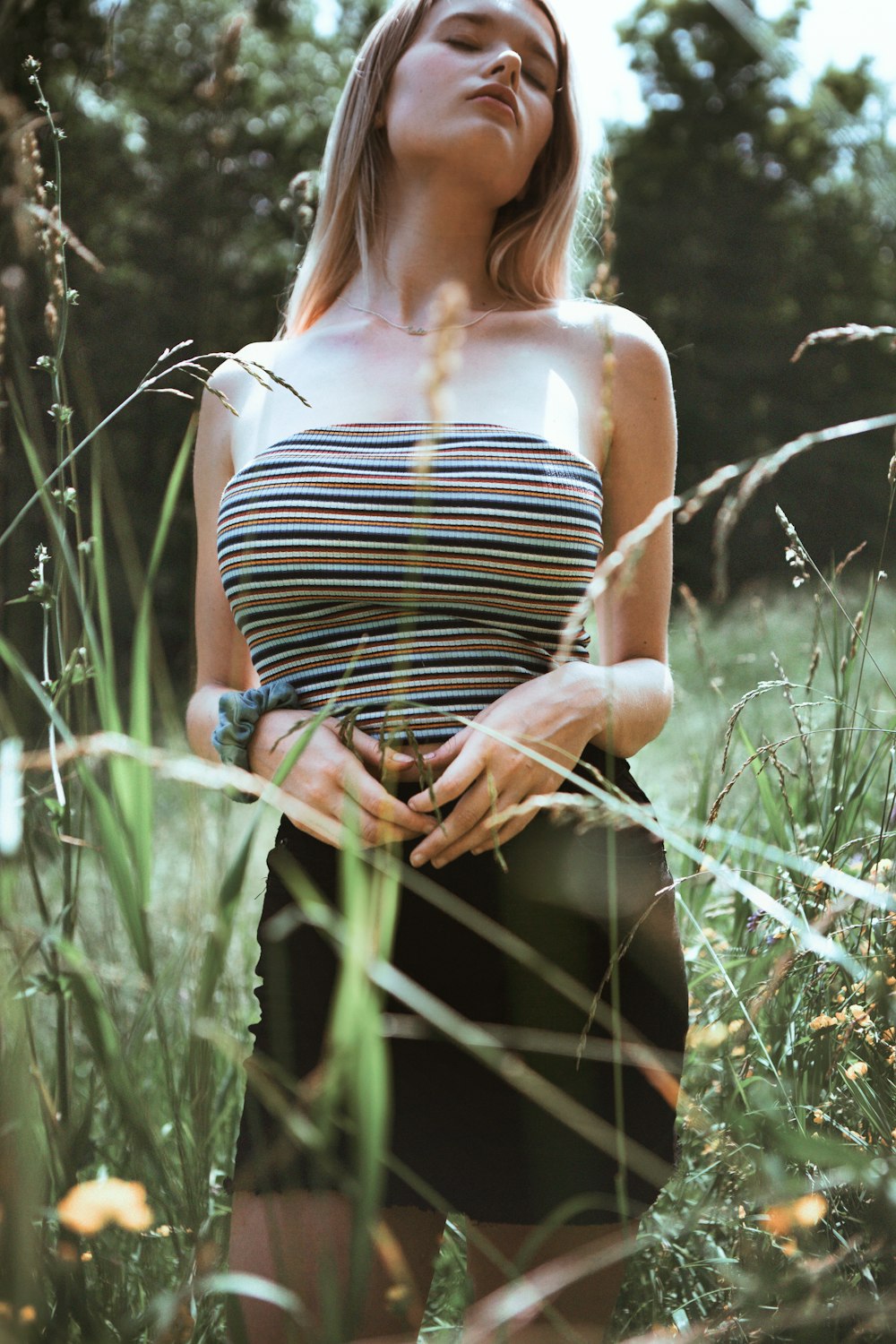 woman in black and white stripe tank top and blue denim daisy dukes standing on green