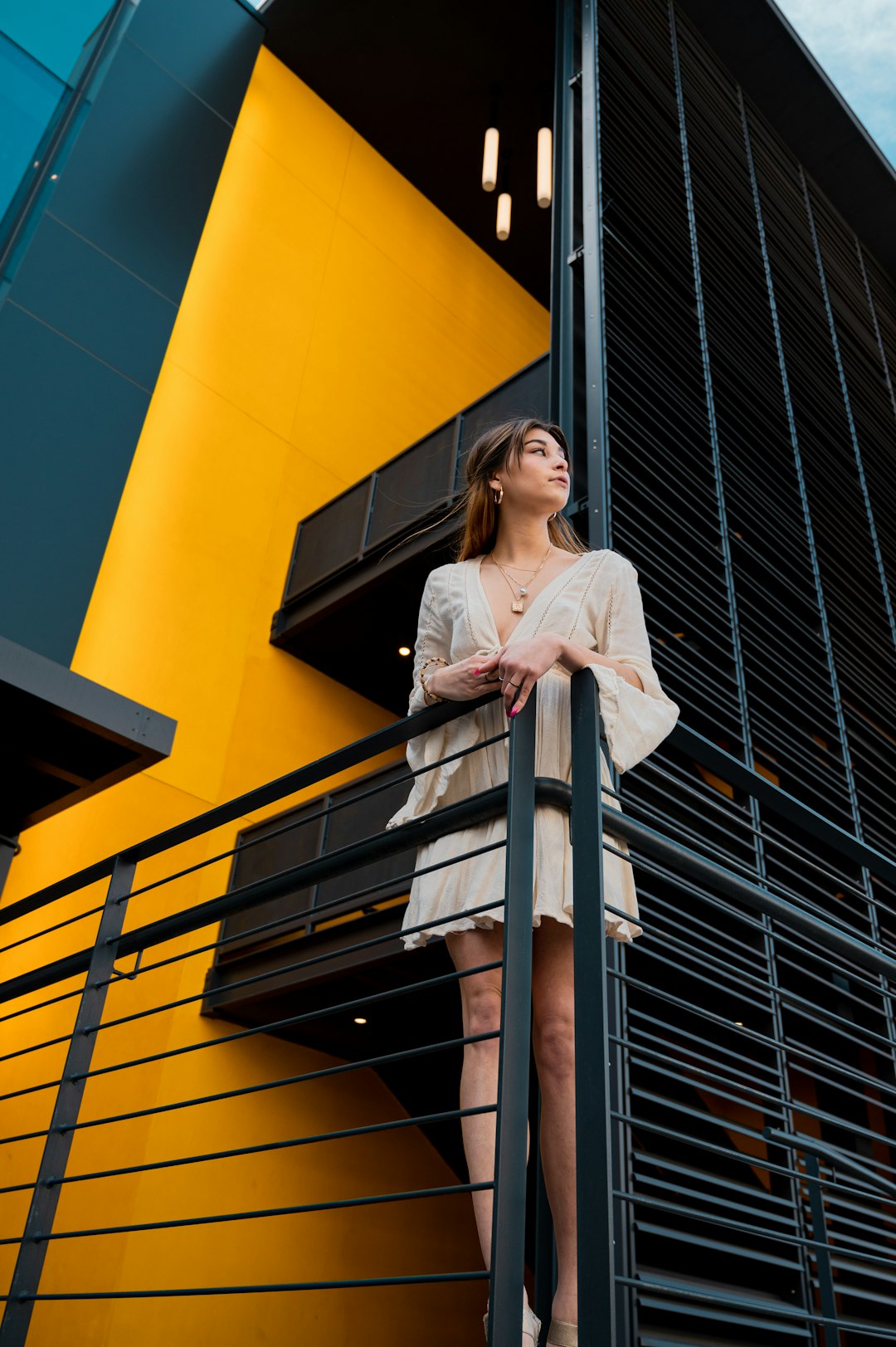 woman in white long sleeve shirt standing on black metal staircase