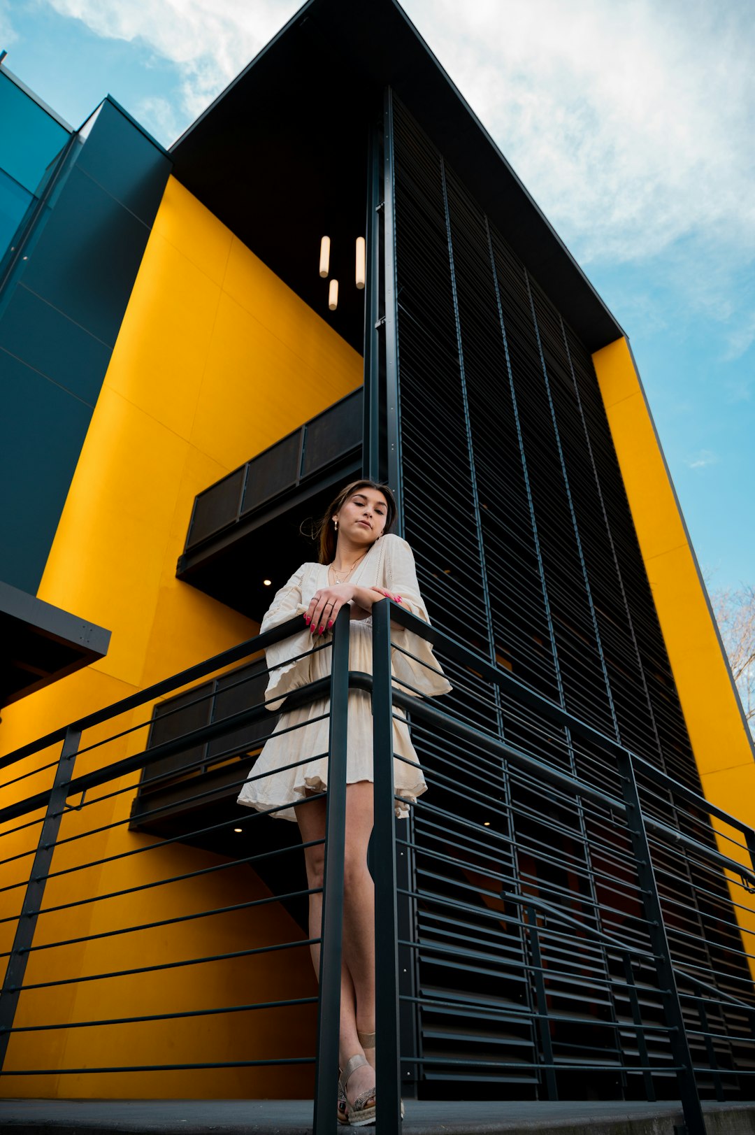 woman in white long sleeve shirt standing beside yellow building during daytime