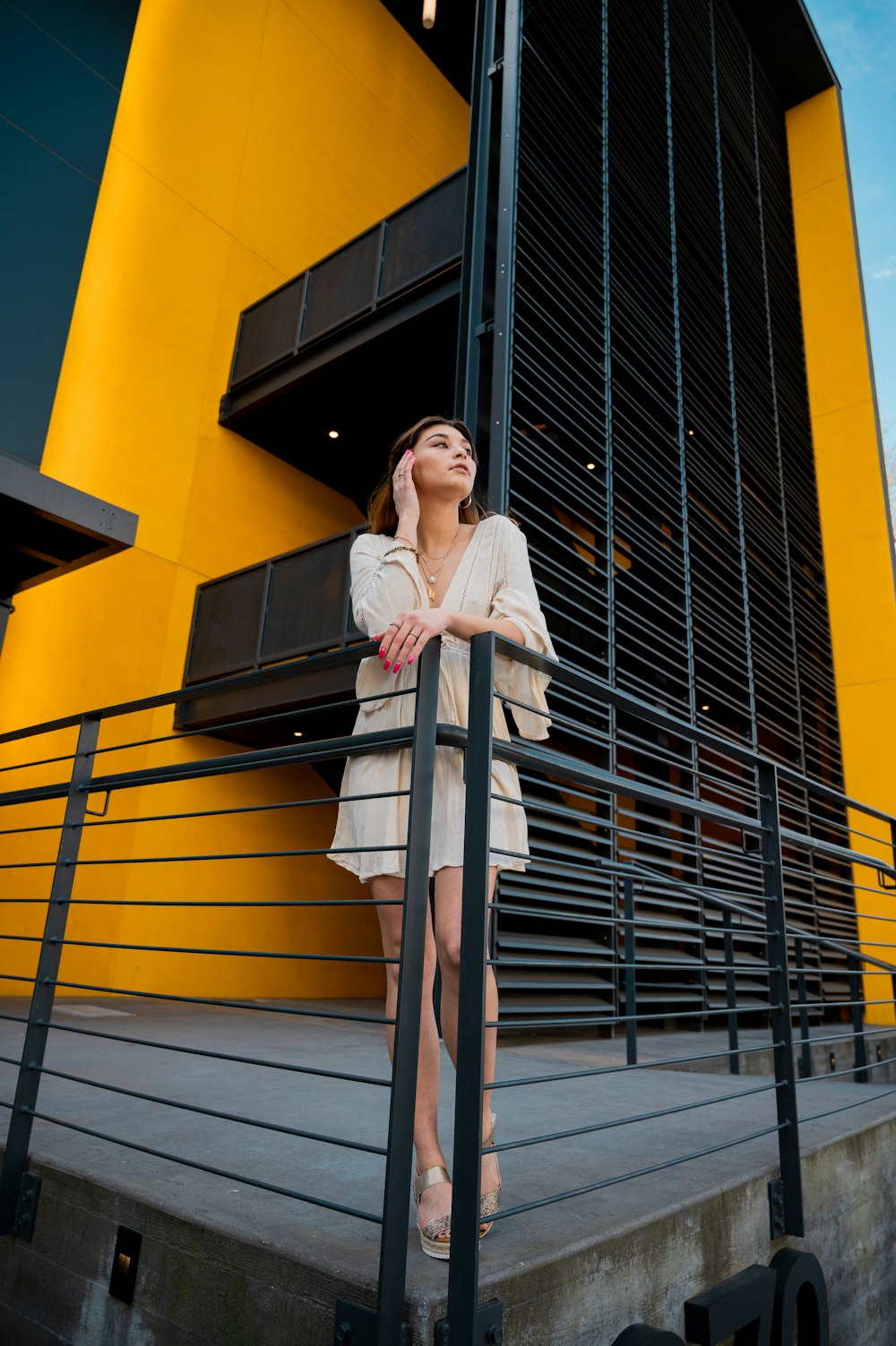 woman in white long sleeve dress standing on yellow staircase