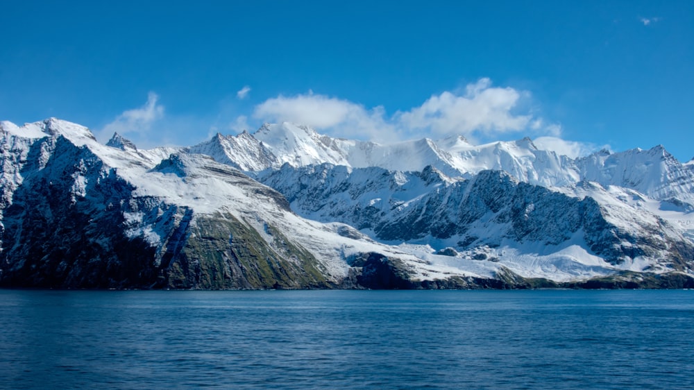 snow covered mountain near body of water during daytime