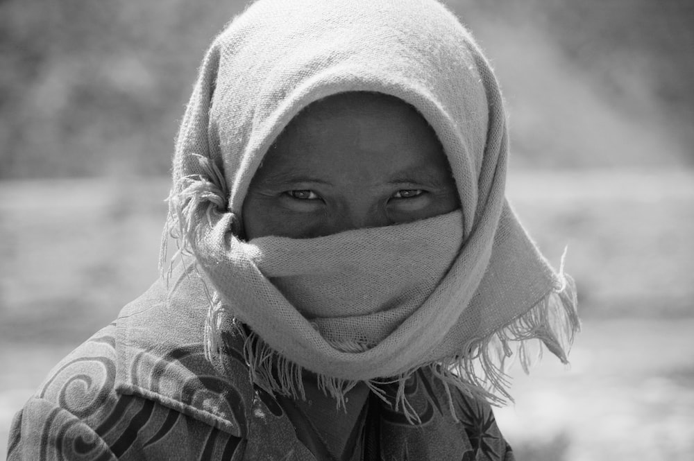 grayscale photo of woman covering her face with white towel