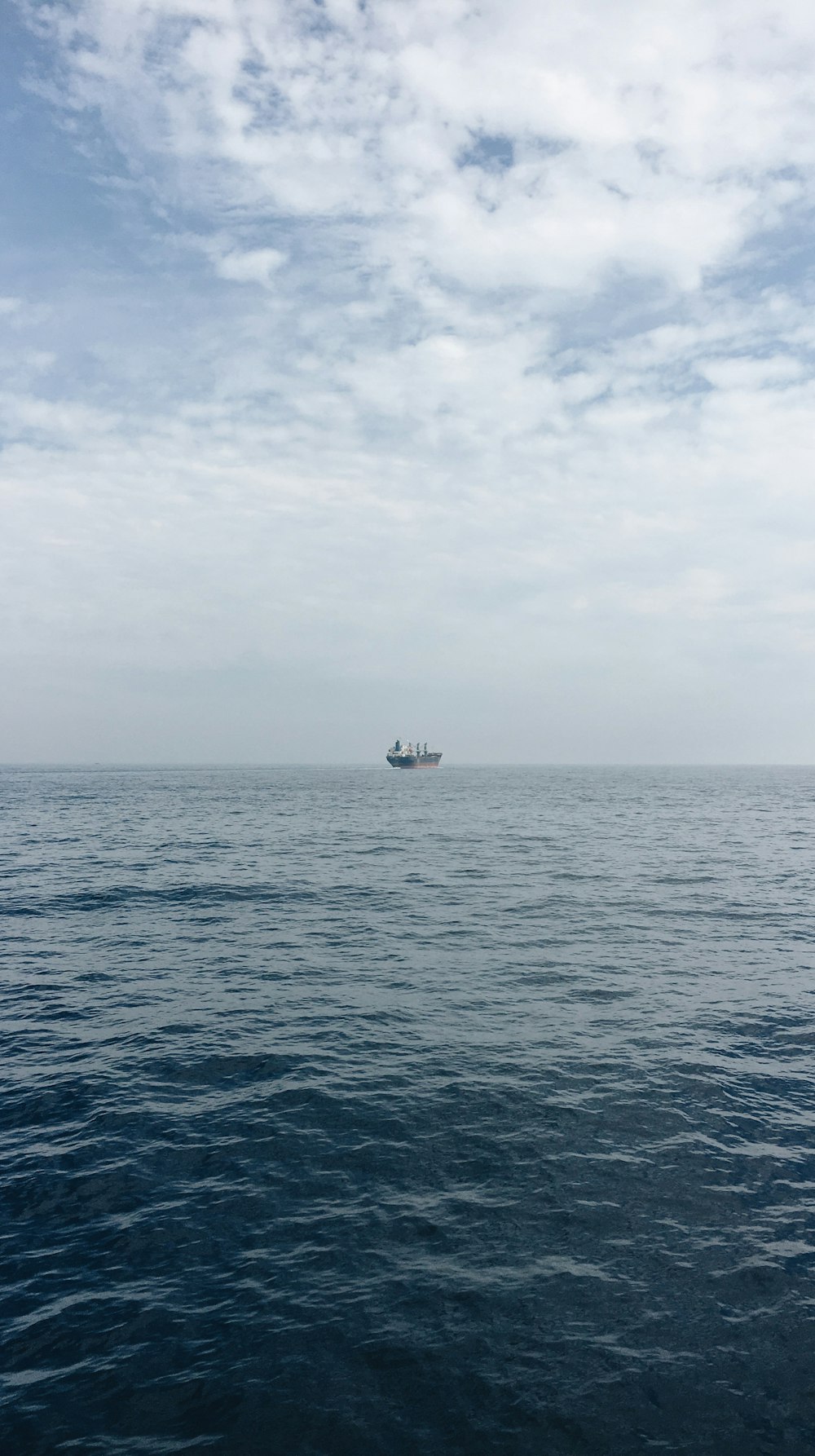 white boat on sea under white clouds during daytime