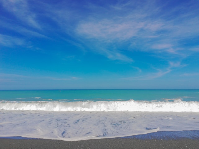 A tranquil beach scene with gentle waves lapping at the shore under a clear blue sky.