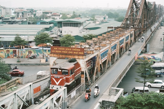 red and white train on rail road during daytime in Cầu Long Biên Vietnam