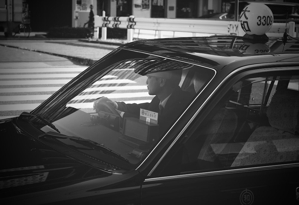 grayscale photo of man in car