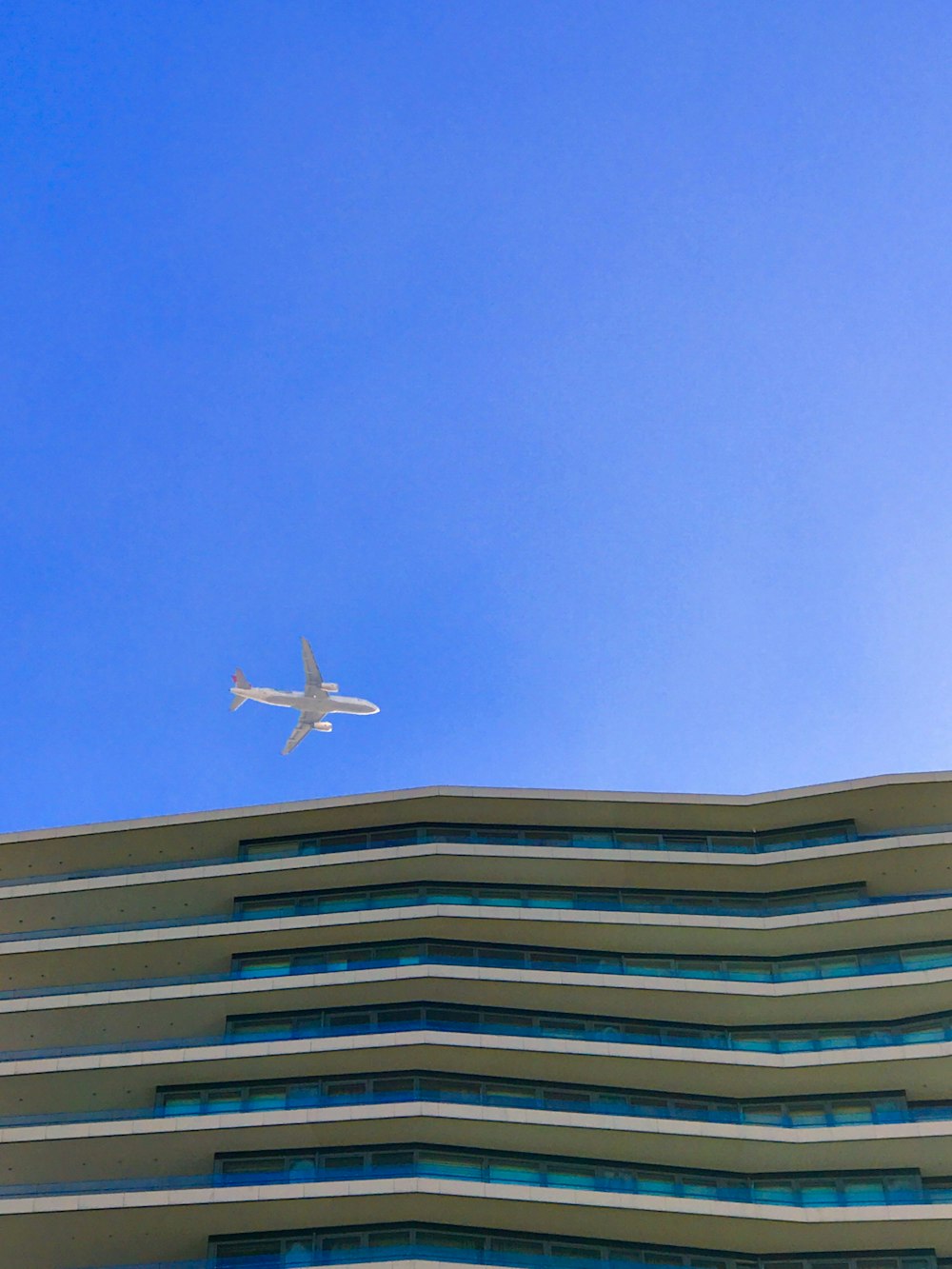 Avión blanco volando sobre un edificio marrón y blanco durante el día