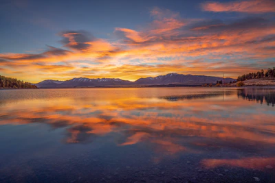 A serene landscape showing a calm lake reflecting a colorful sunset.