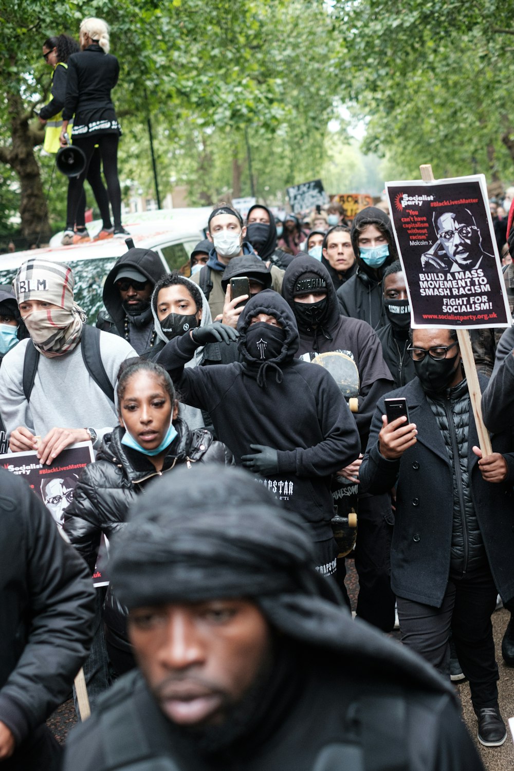 people in black jacket holding red and white banner