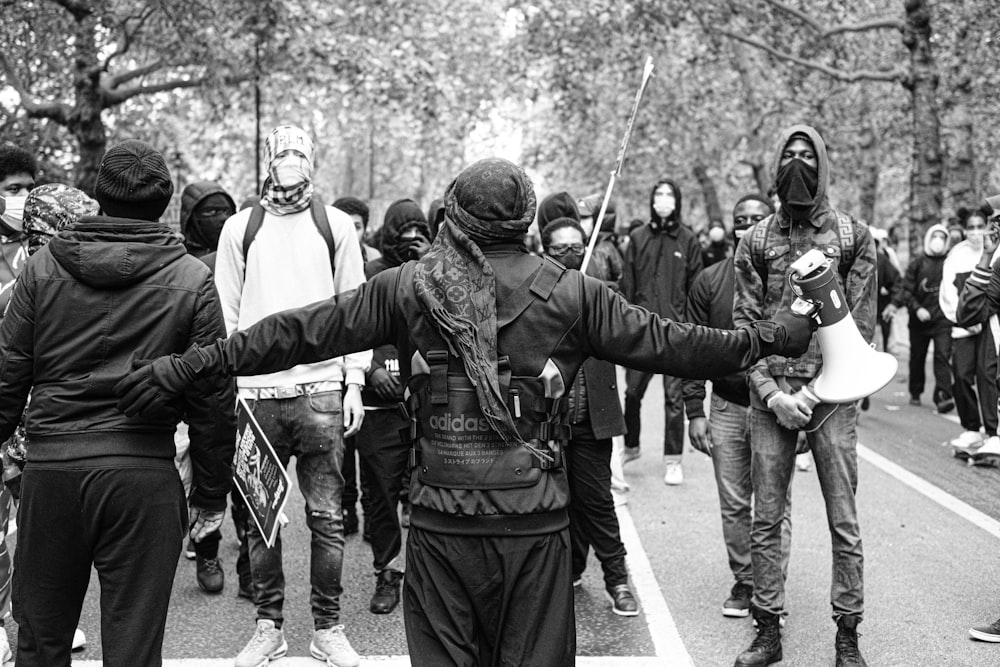 Grupo de hombres con uniforme de camuflaje verde y negro de pie en una carretera de concreto gris durante el día