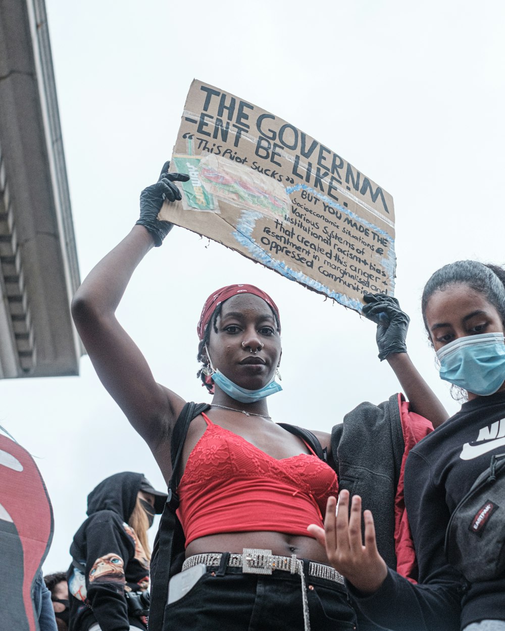 man in red tank top wearing white face mask holding banner