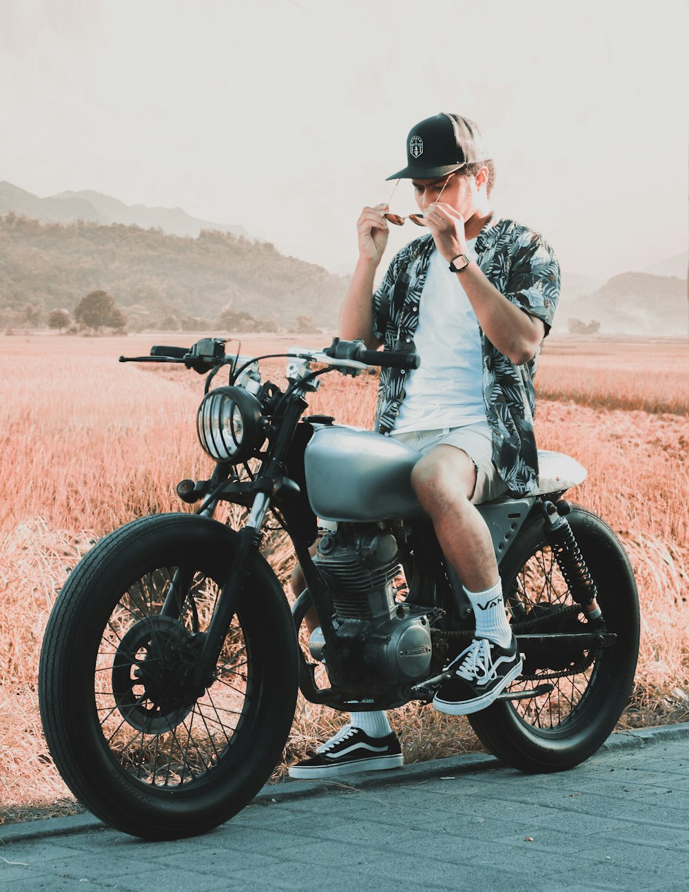 man in white and black floral dress shirt riding black motorcycle during daytime