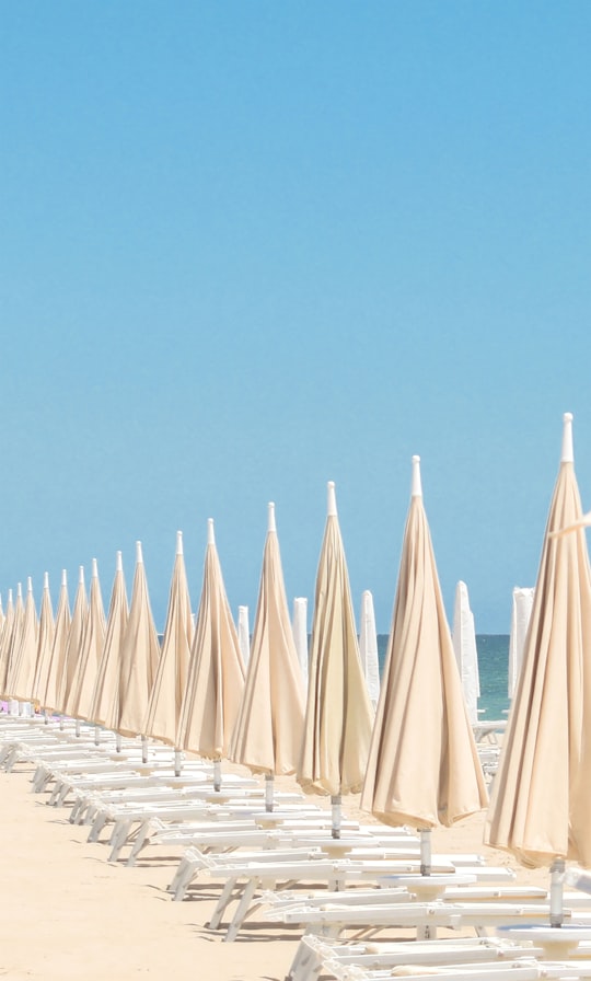 white and blue umbrellas on beach during daytime in Rimini Italy