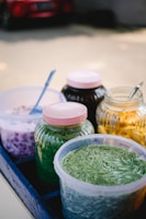 Colorful jars filled with various no-cook fillings arranged on a wooden table.