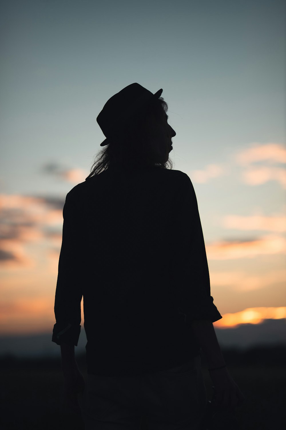 silhouette of woman wearing hat during sunset