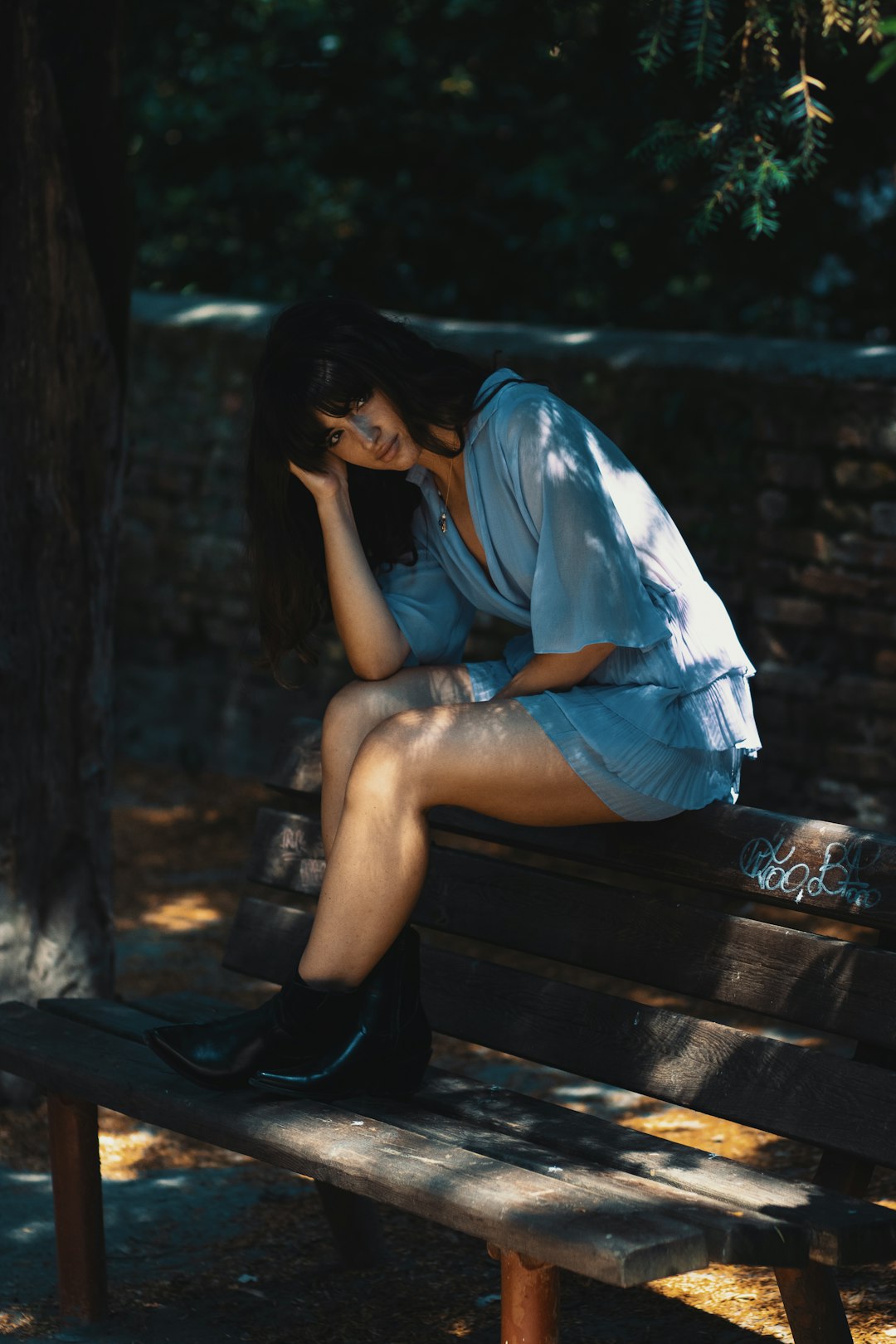 woman in blue shirt sitting on brown wooden bench