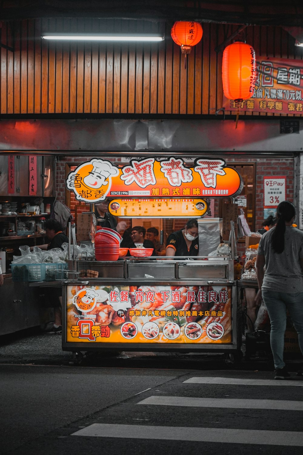 man in black jacket standing in front of food stall