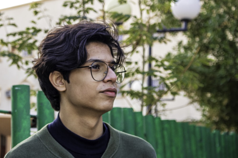 Hombre con camisa verde de cuello redondo con gafas de montura negra