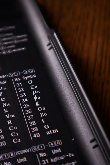 A close-up view of a calculator or electronic device with a black background. White alphanumeric symbols and numbers are visible, indicating various mathematical or scientific units.