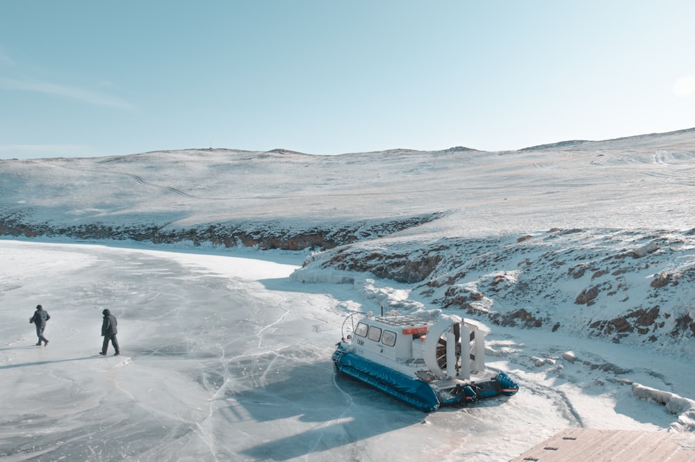 weiß-blaues Boot tagsüber auf schneebedecktem Boden