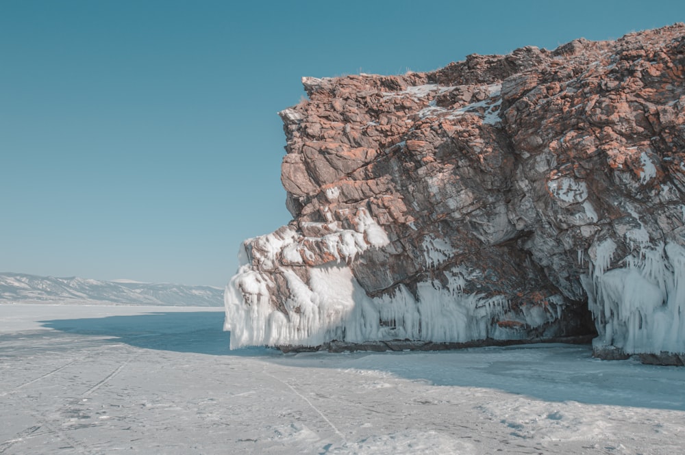 brown rock formation on white snow covered ground under blue sky during daytime