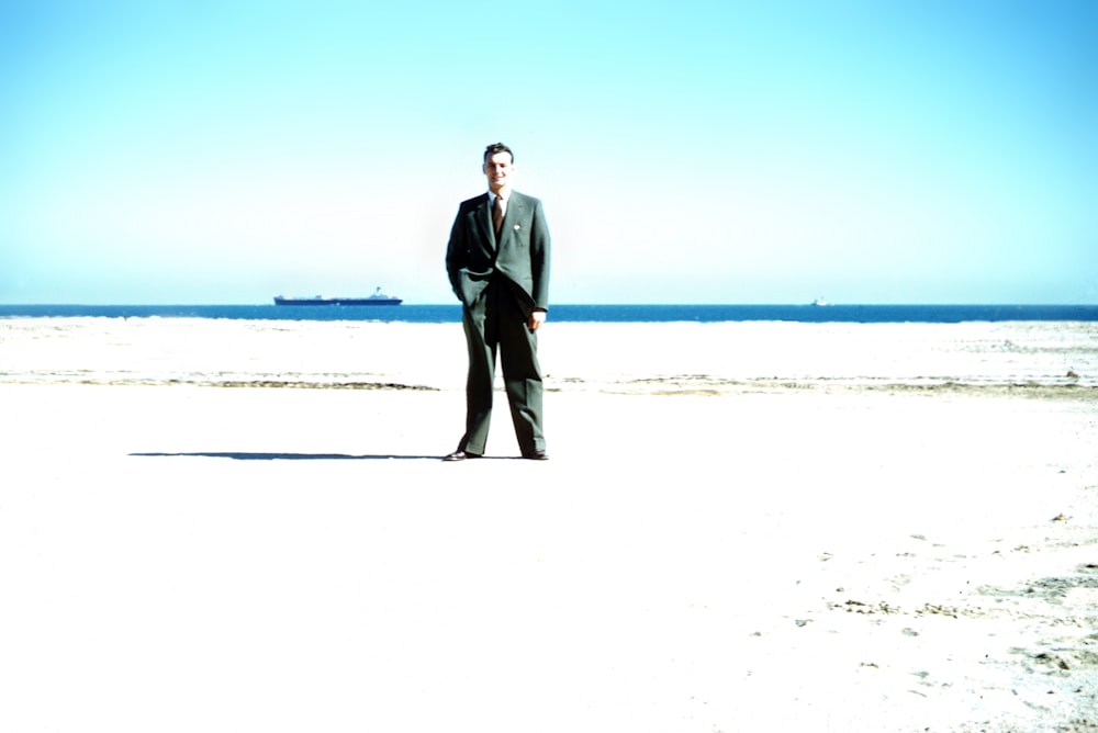 man in black suit standing on white sand during daytime