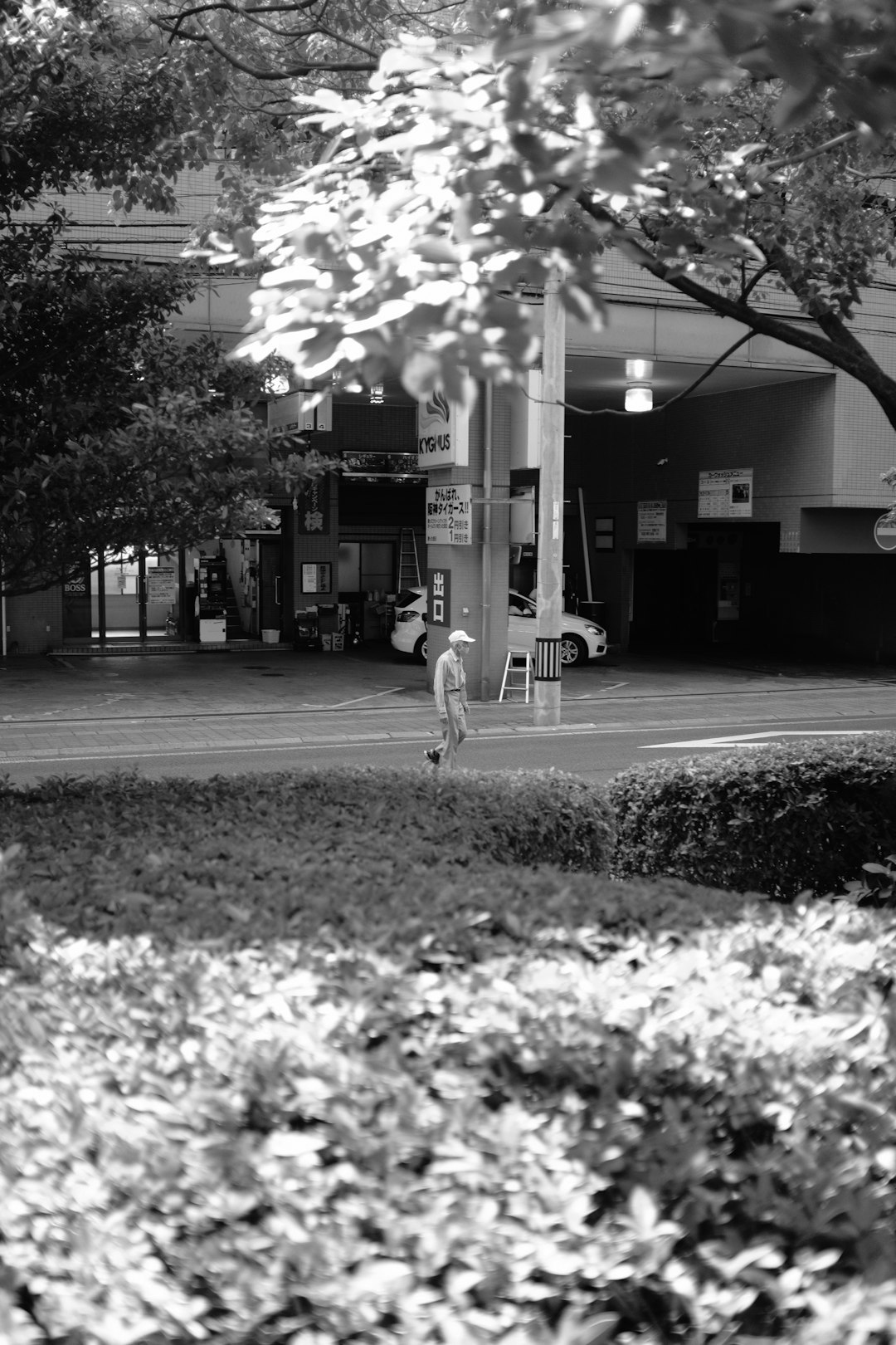 grayscale photo of woman walking on sidewalk