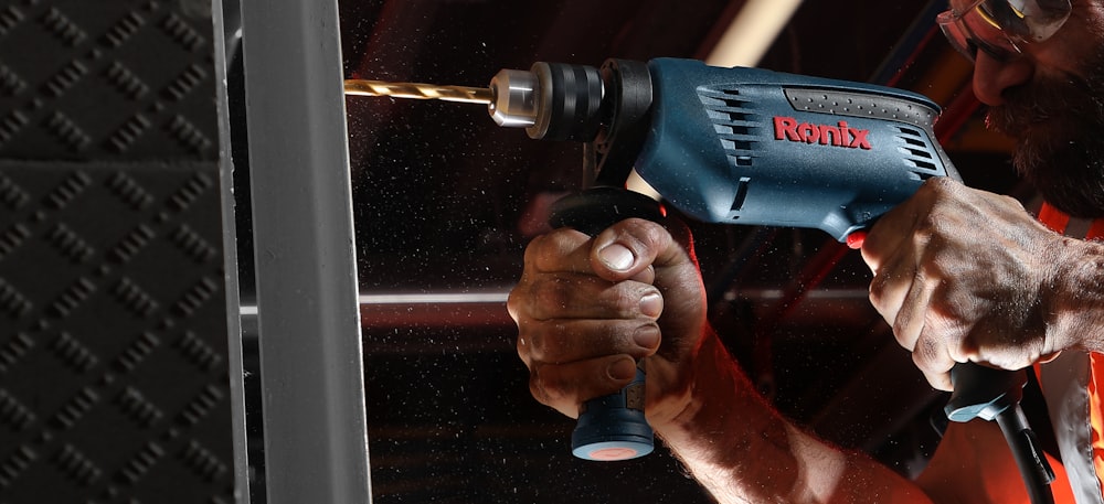 person holding blue and black cordless power drill
