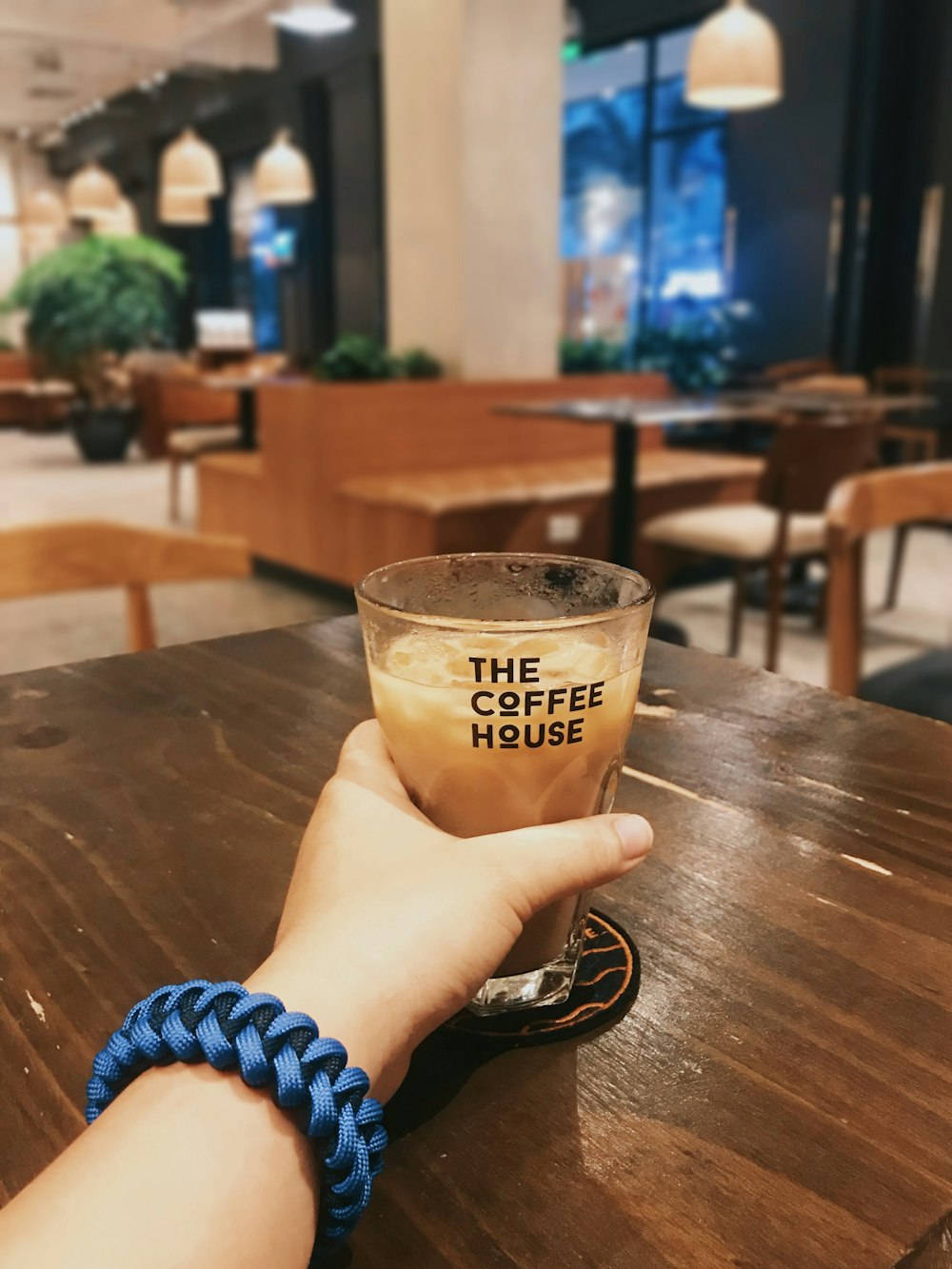 person holding clear drinking glass with brown liquid