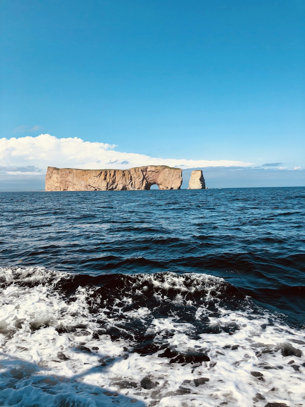 formação rochosa marrom no mar sob o céu azul durante o dia