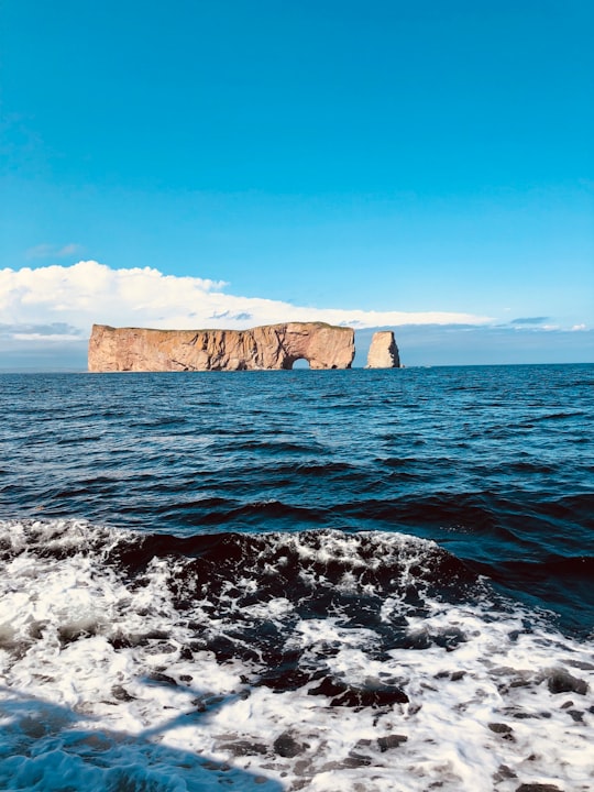 brown rock formation on sea under blue sky during daytime in Percé Rock Canada