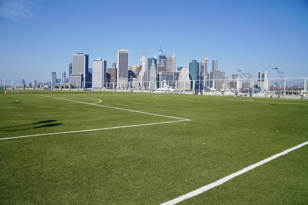 green grass field near city buildings during daytime
