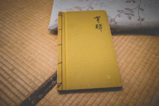 Close-up of a worn martial arts manual with Japanese calligraphy on the cover, resting on a wooden table.