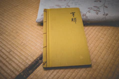Close-up of a worn martial arts manual with Japanese calligraphy on the cover, resting on a wooden table.